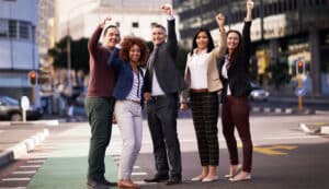 5 Personen stehen jubelnd auf einer Straße